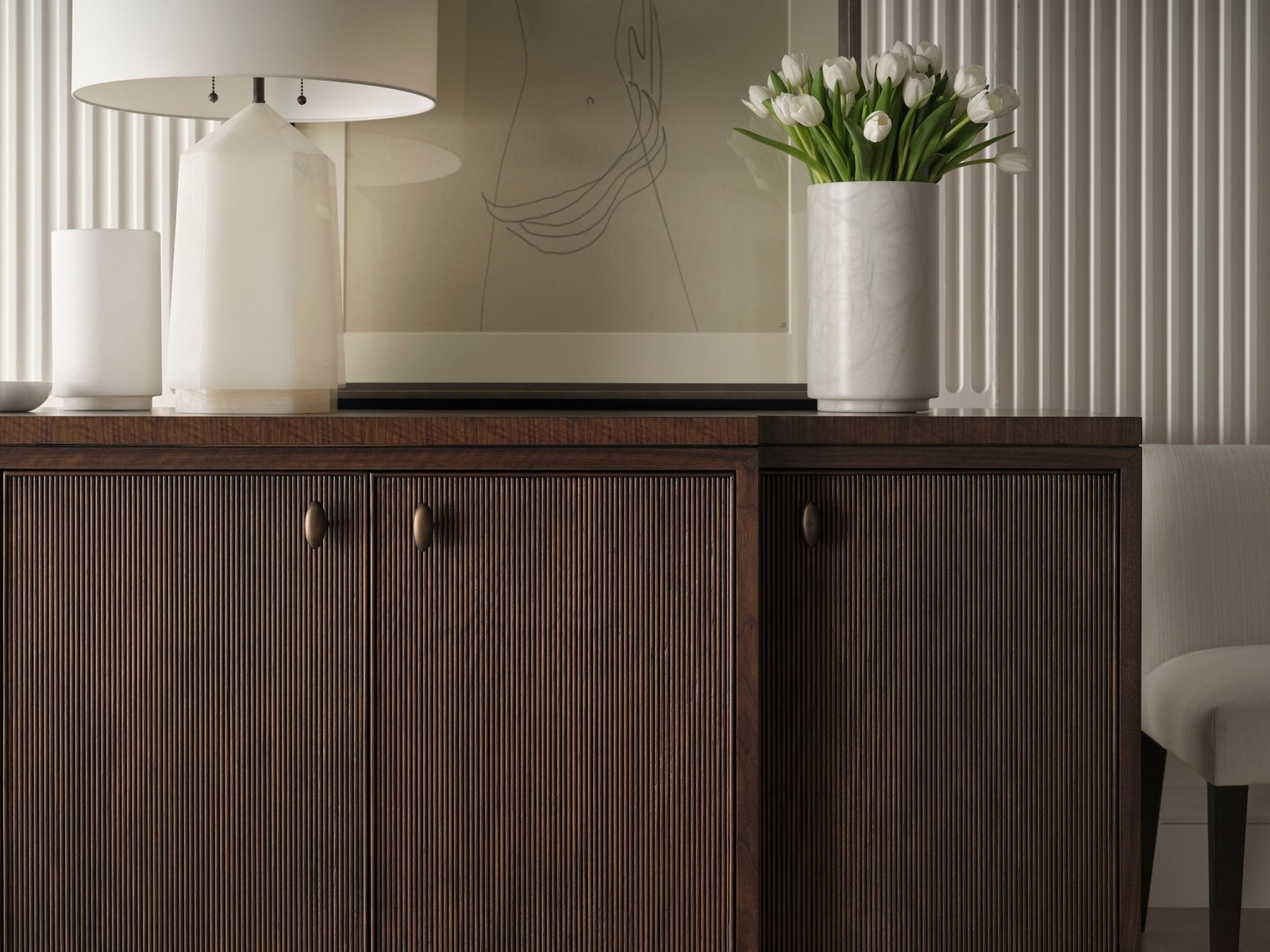 Baker Jensen Console with a reeded walnut front styled with a lamp and fresh flowers